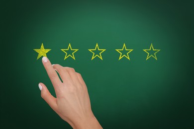 Image of Quality evaluation. Woman touching golden star on green chalkboard, closeup