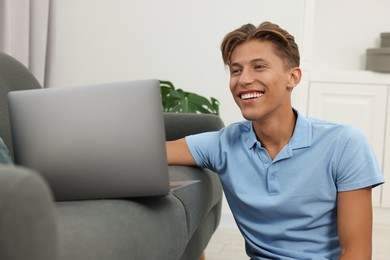 Happy young man having video chat via laptop indoors