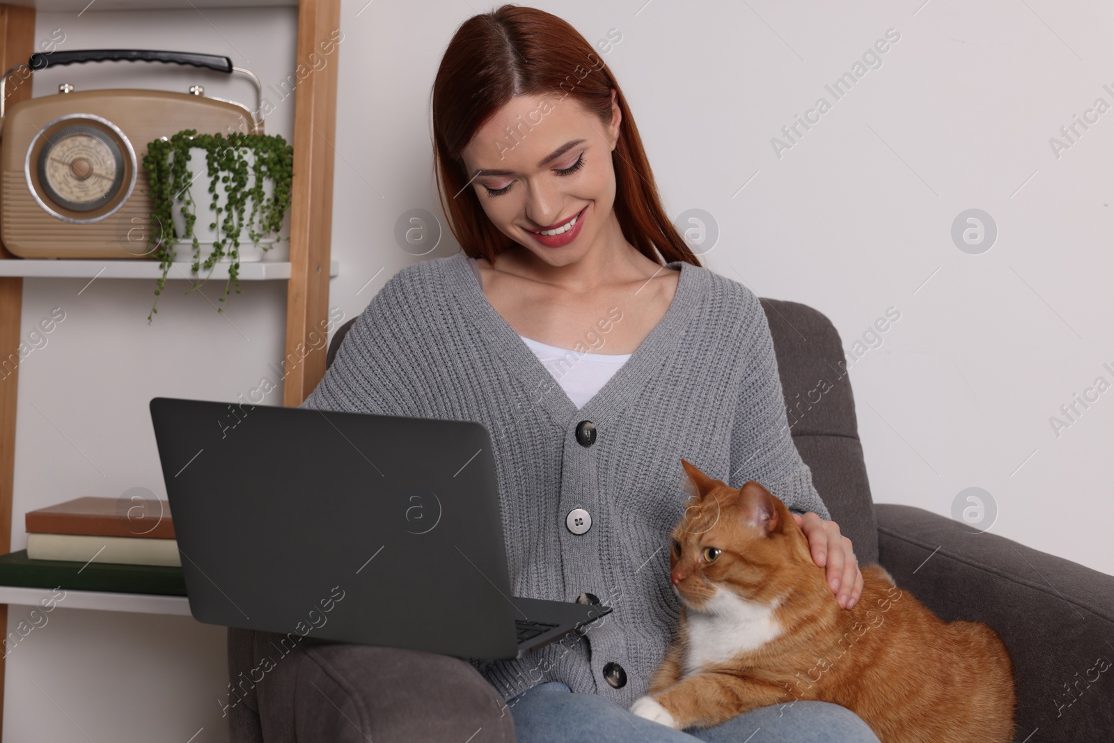 Photo of Happy woman with cat working in armchair at home