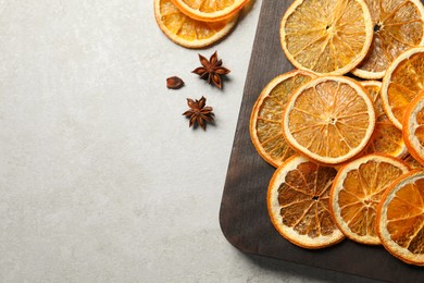 Photo of Dry orange slices and anise stars on light grey table, flat lay. Space for text