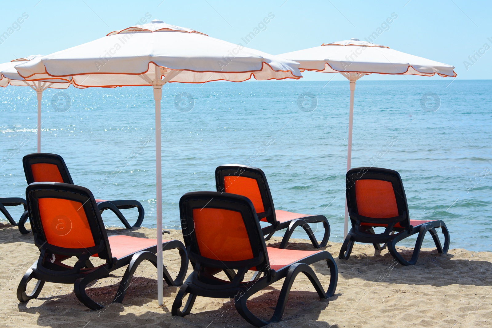 Photo of Empty sunbeds and beach umbrellas at tropical resort on sunny day