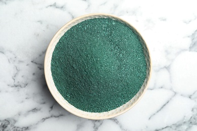 Photo of Bowl of spirulina algae powder on marble background, top view