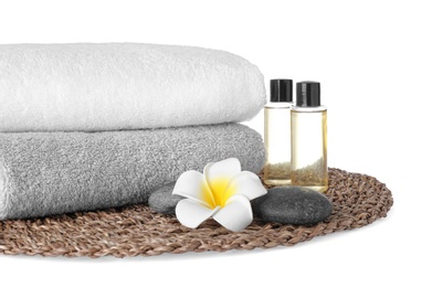Photo of Mat with towels, essential oils and spa stones on white background