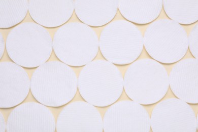 Many clean cotton pads on yellow background, flat lay
