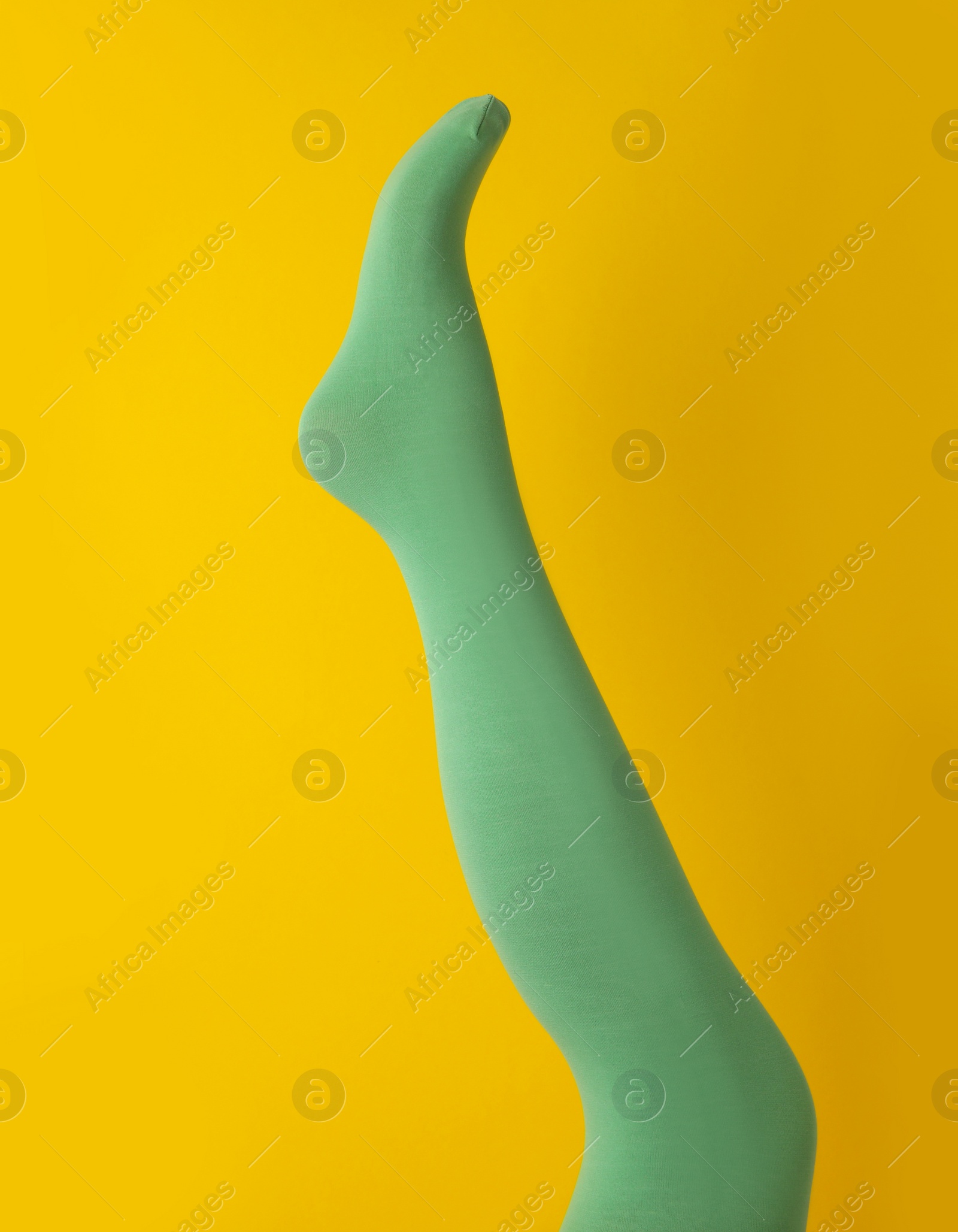 Photo of Leg mannequin in green tights on yellow background