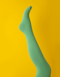Photo of Leg mannequin in green tights on yellow background