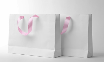 Photo of Paper shopping bags with ribbon handles on white background. Mockup for design