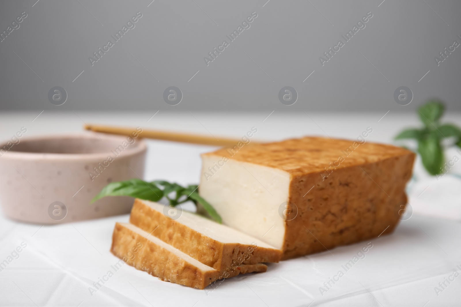 Photo of Delicious smoked tofu, soy sauce and basil on tiled table