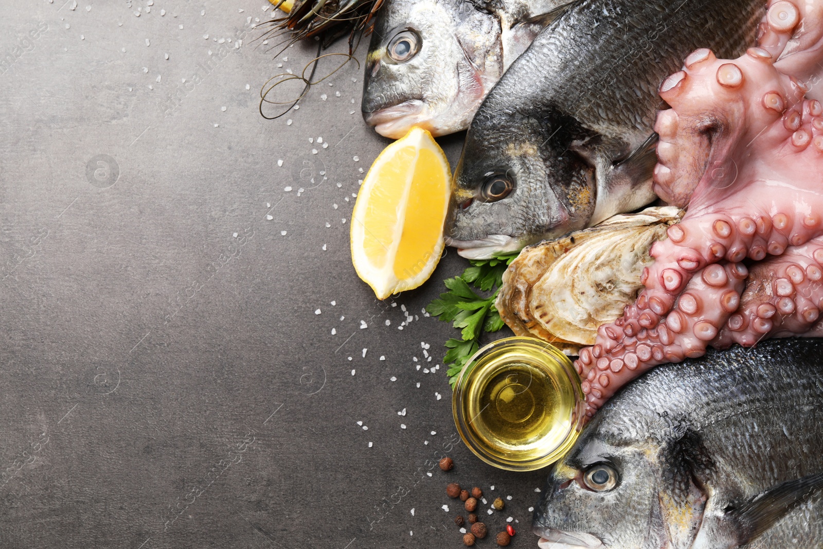 Photo of Flat lay composition with fresh raw dorado fish and different seafood on grey table. Space for text