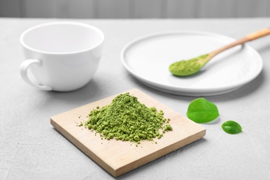 Wooden board with powdered matcha tea on table