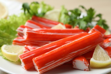 Photo of Delicious crab sticks with lemon on plate , closeup