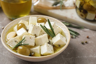 Composition with pickled feta cheese in bowl on light brown table