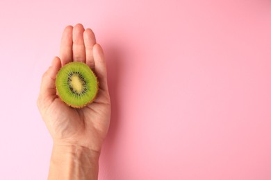 Woman holding delicious fresh kiwi on pink background, top view. Space for text