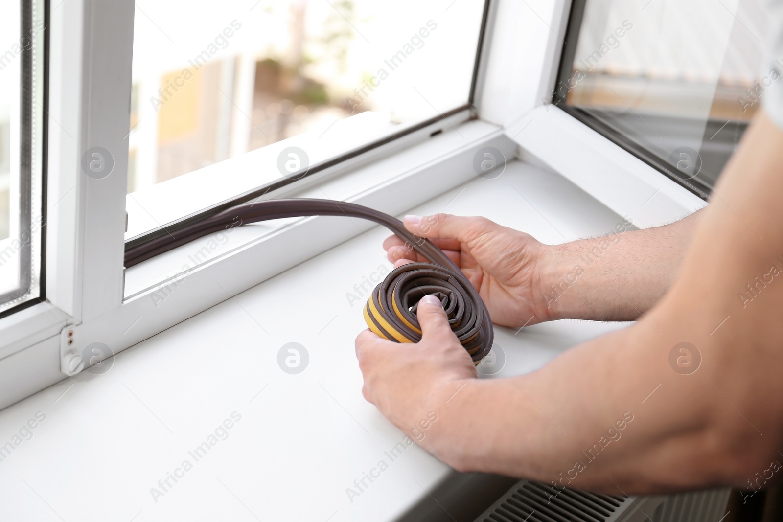 Photo of Construction worker putting sealing foam tape on window indoors