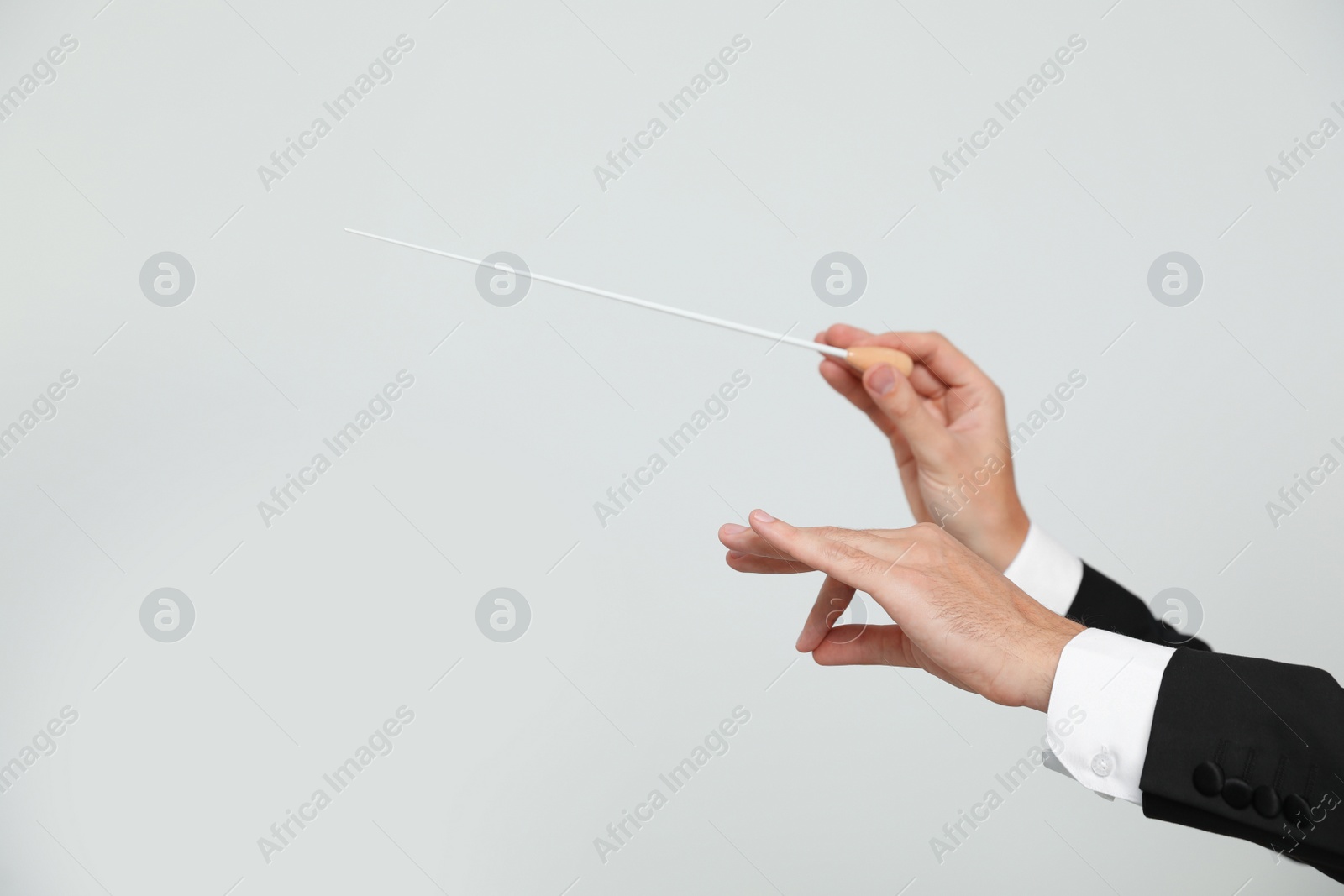 Photo of Professional conductor with baton on light grey background, closeup. Space for text