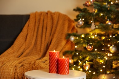 Photo of Beautiful candles near Christmas tree indoors. Cosy atmosphere