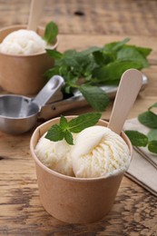 Paper cups with delicious ice cream and mint on wooden table