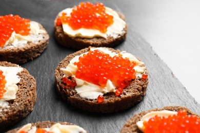 Photo of Delicious sandwiches with red caviar on slate plate