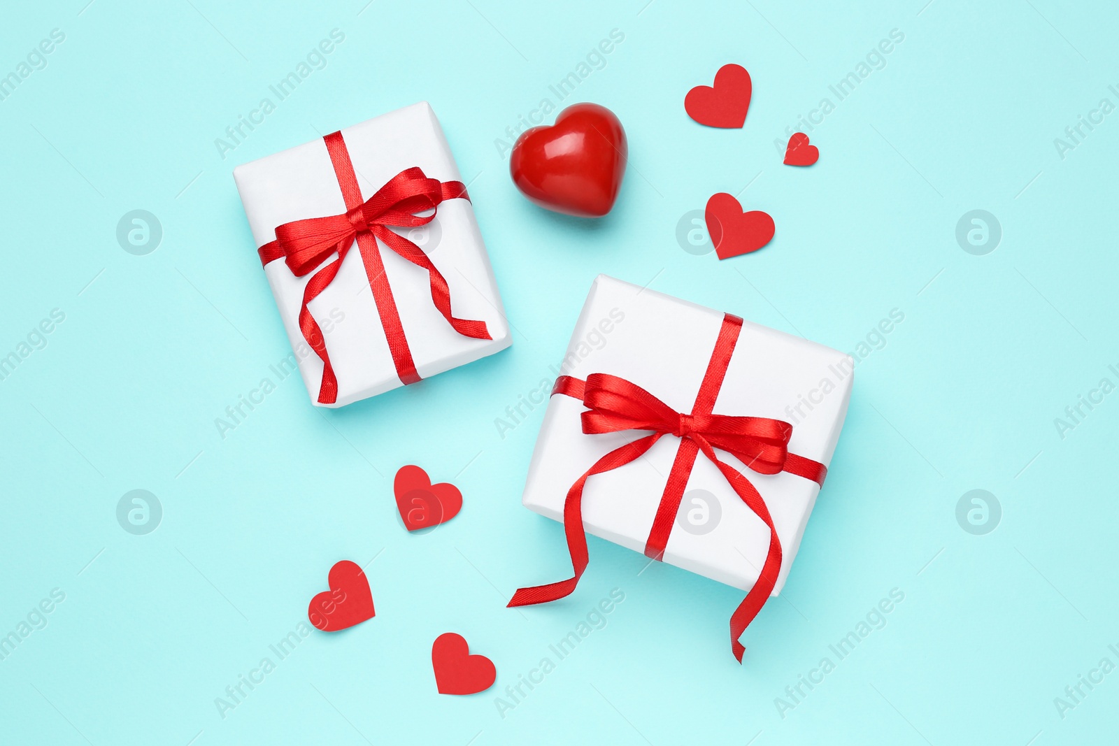 Photo of Gift boxes with decorative red hearts on turquoise background, flat lay