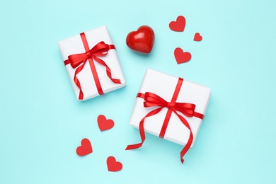 Gift boxes with decorative red hearts on turquoise background, flat lay