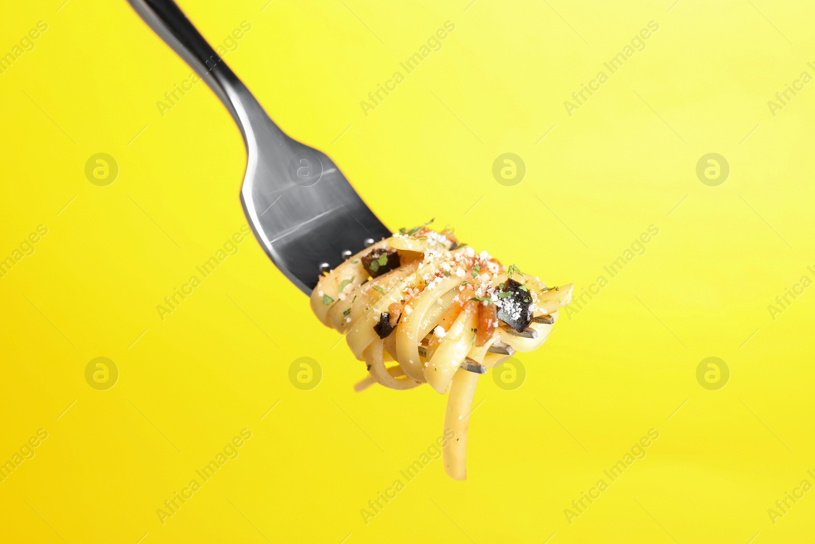 Photo of Fork with tasty pasta on yellow background, closeup