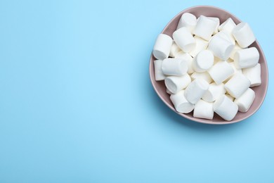 Photo of Delicious puffy marshmallows on light blue background, top view. Space for text