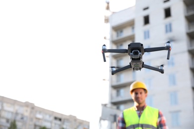 Builder operating drone with remote control at construction site, focus on quadcopter. Aerial survey