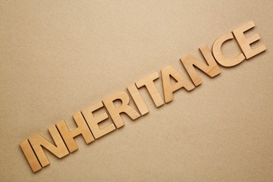 Word Inheritance made with wooden letters on beige background, flat lay