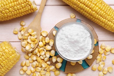 Photo of Bowl with corn starch, ripe cobs and kernels on wooden table, flat lay