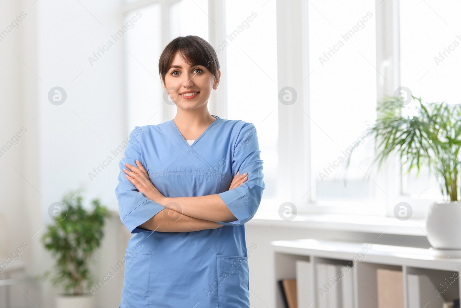 Photo of Portrait of smiling medical assistant with crossed arms in hospital. Space for text