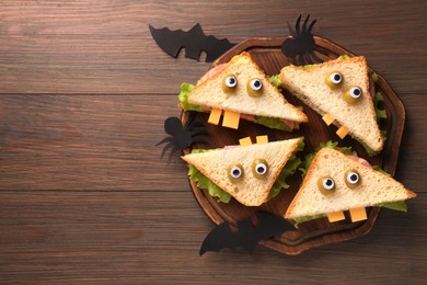 Photo of Tasty monster sandwiches and Halloween decorations on wooden table, flat lay. Space for text