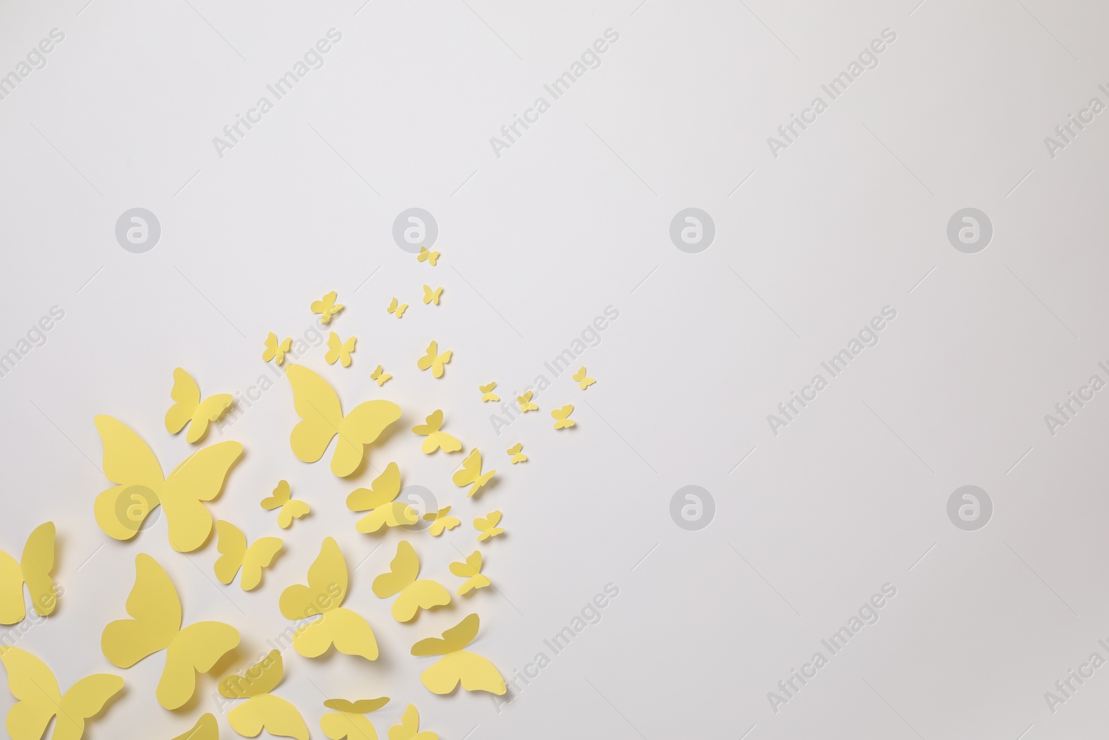 Photo of Yellow paper butterflies on white background, top view. Space for text