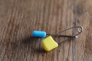 New safety pins on wooden table, closeup. Space for text