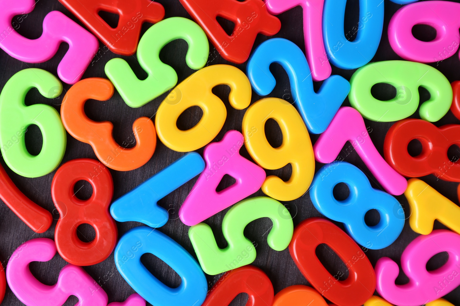 Photo of Colorful numbers on dark wooden school desk, top view