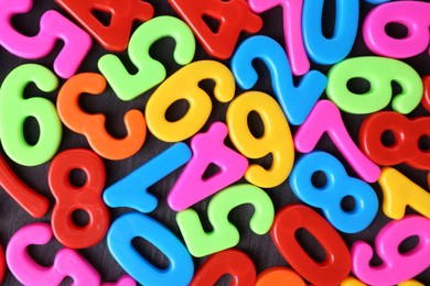 Colorful numbers on dark wooden school desk, top view