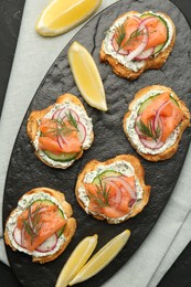 Tasty canapes with salmon, cucumber, radish and cream cheese on table, top view