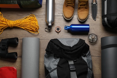 Photo of Flat lay composition with different camping equipment on wooden background
