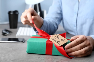 Photo of Man opening present from secret Santa at workplace, closeup