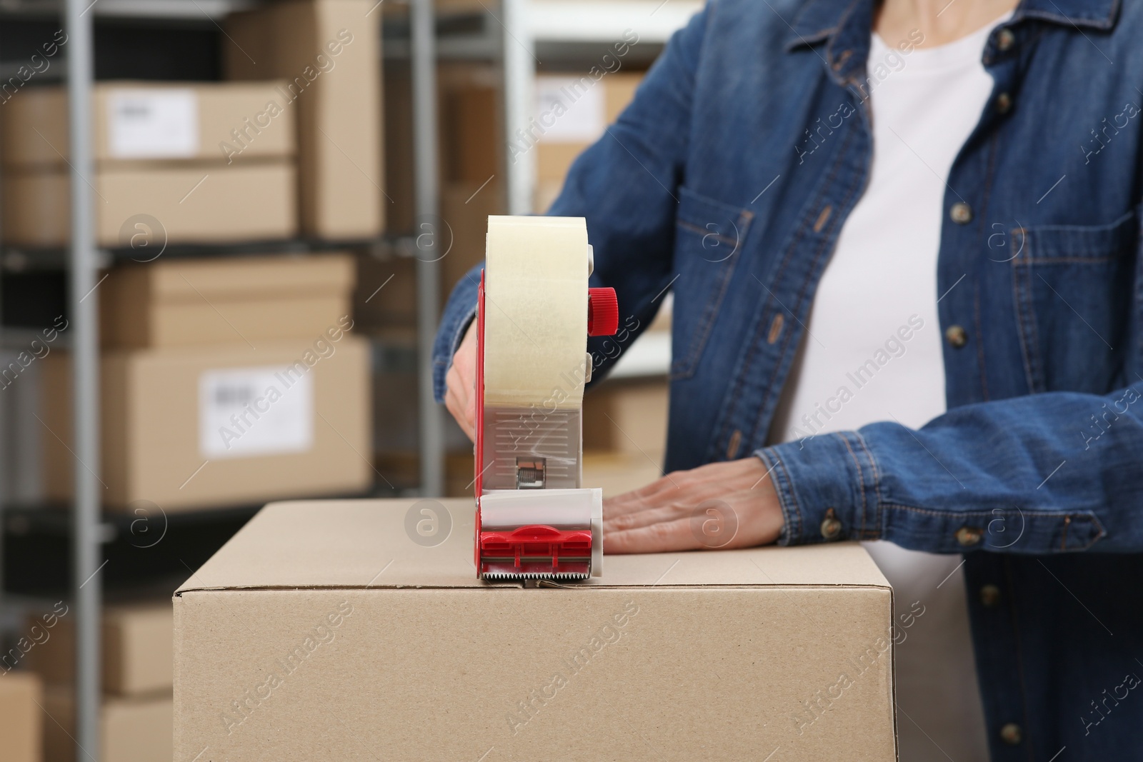 Photo of Seller taping parcel in office, closeup. Online store