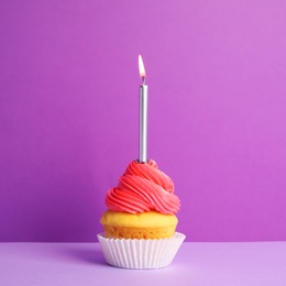 Birthday cupcake with candle on violet background