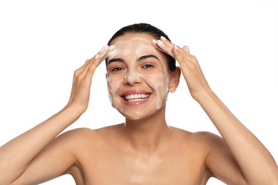 Photo of Happy young woman washing face with cosmetic product on white background