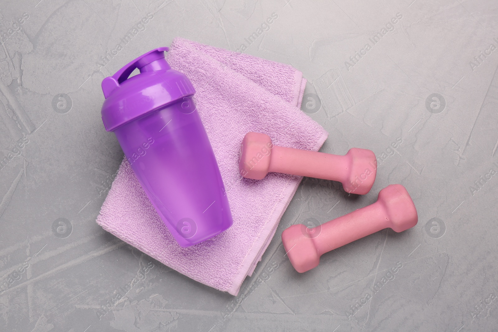 Photo of Dumbbells, water shaker and towel on light grey table, flat lay