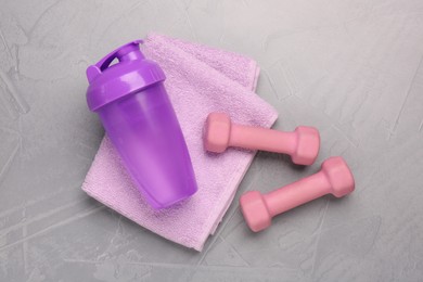Dumbbells, water shaker and towel on light grey table, flat lay