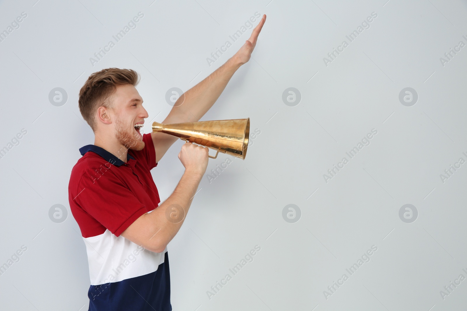 Photo of Young man with megaphone on light background. Space for text