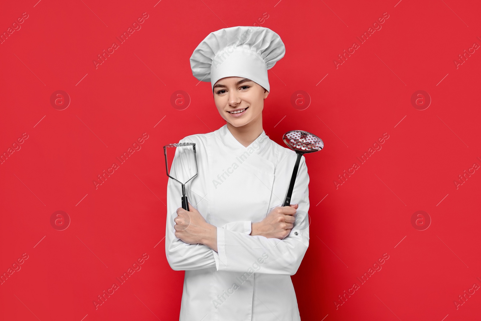 Photo of Professional chef with potato pusher and skimmer on red background