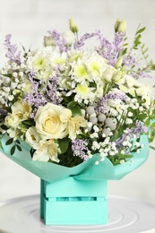 Photo of Beautiful bouquet of flowers in decorative crate on table against light background