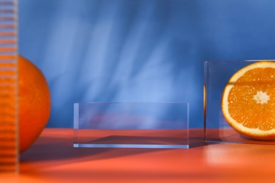 Presentation for product. Podium and tasty fresh oranges on red table against blue background, closeup. Space for text