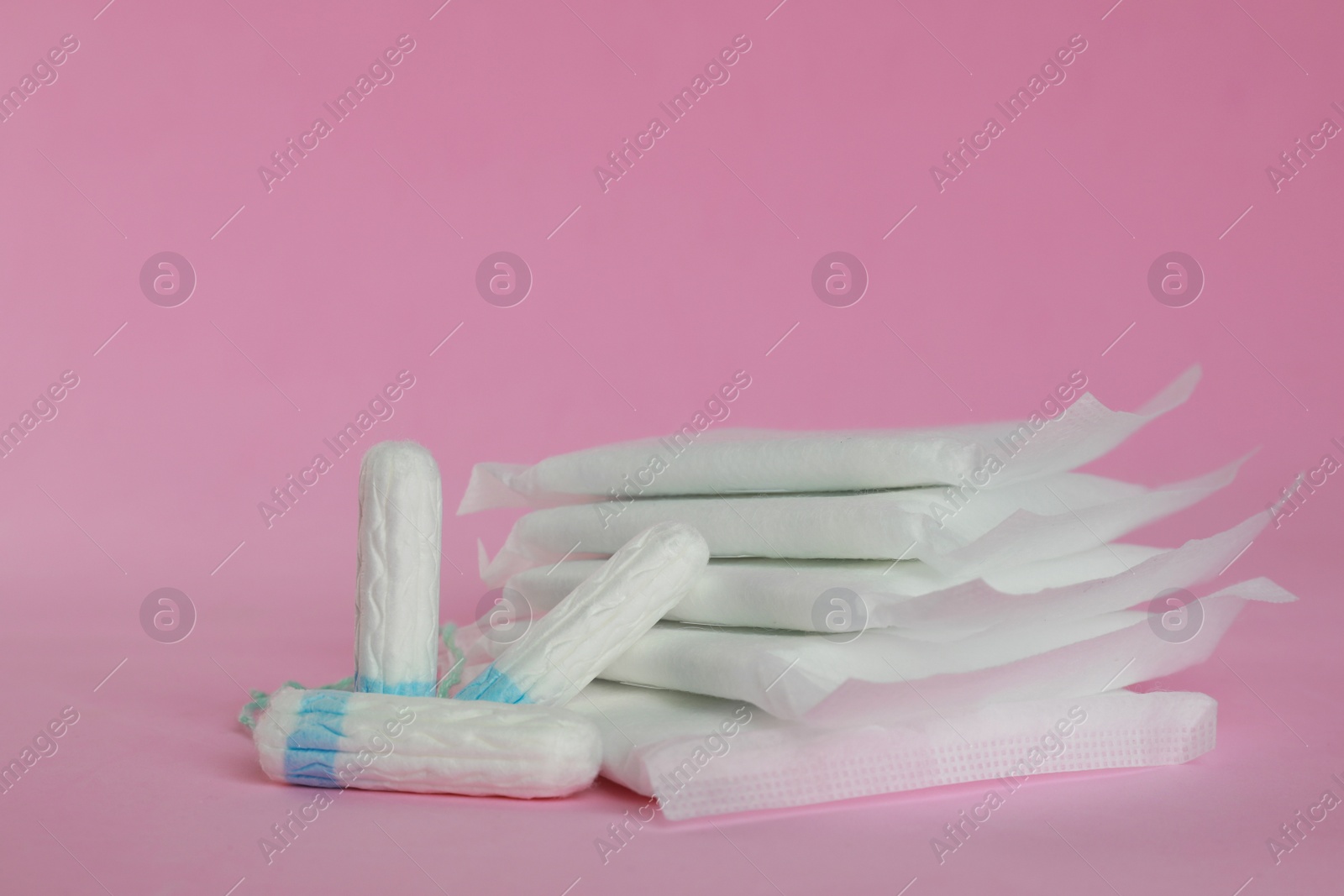 Photo of Menstrual pads and tampons on pink background