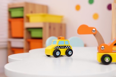 Photo of Cute wooden cars on table in kindergarten, closeup. Space for text