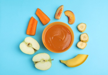 Photo of Baby food in bowl and fresh ingredients on light blue background, flat lay